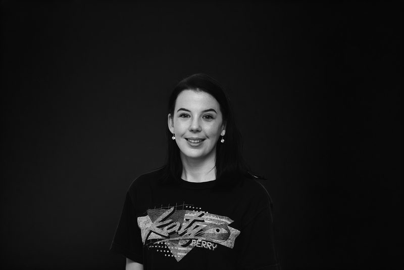 Black and white headshot of a smiling woman with dark hair in a graphic t-shirt