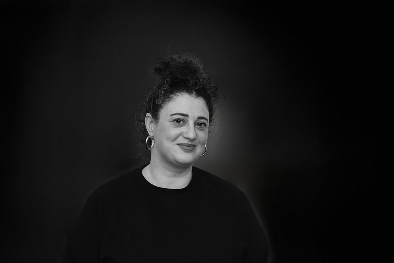 Black and white headshot of a smiling woman with curly hair pinned up
